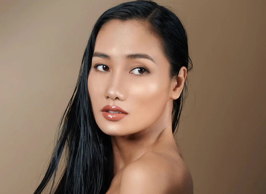 A woman with dark hair and a white tank top looks over her shoulder at the camera - Picosure Laser in Chino, CA