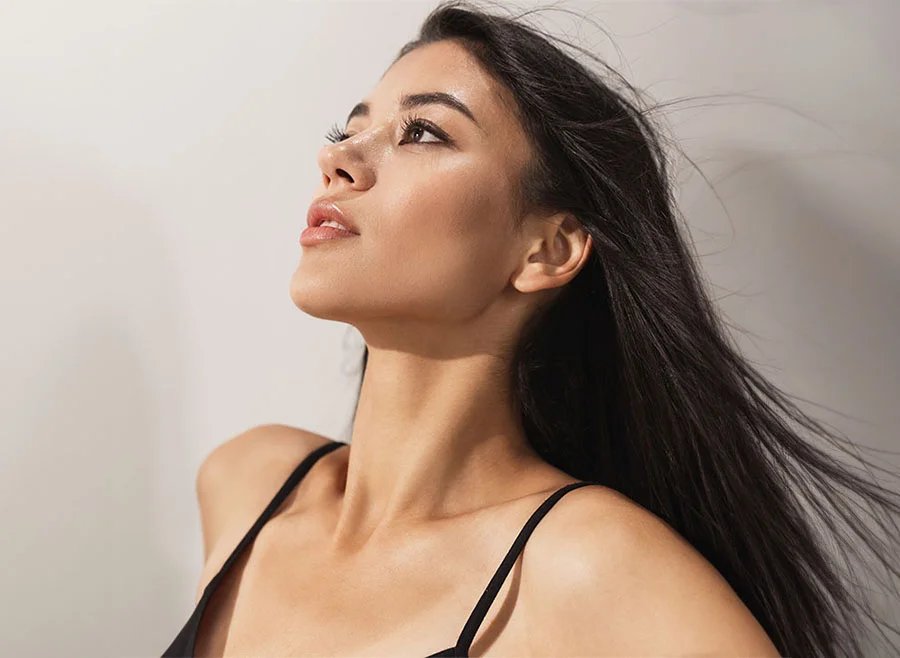 Woman with long dark hair, flowing in the wind as she gazes upwards - RF Microneedling in Chino, CA